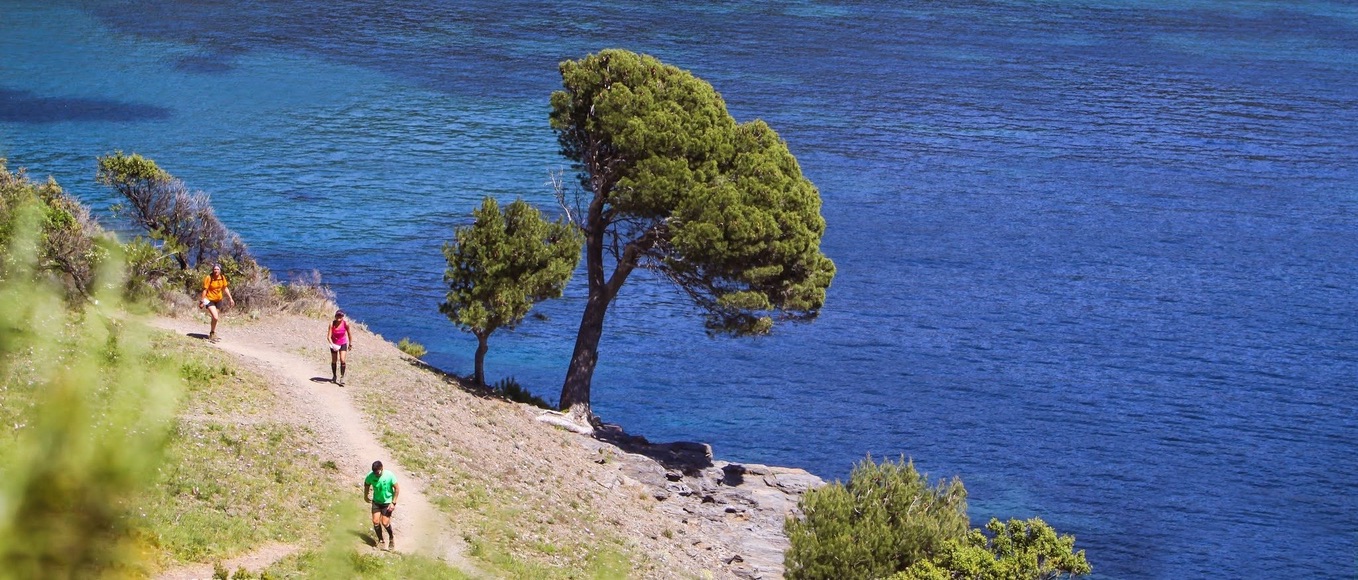 Runners on a coastal path above deep blue Mediterranean water